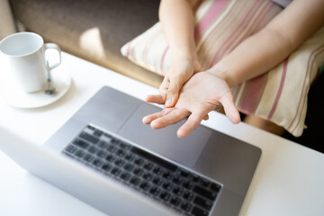 Asian female employee massaging palms with her hand,physical feeling numbness in palm and fingers while typing on keyboard for long period of time,Office worker having pain and sore in hand and wrist