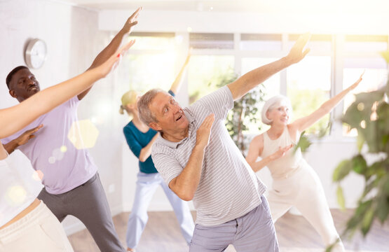 Enthusiastic elderly gentleman immersing in world of contemporary dance with diverse group of adults, performing dabbing move