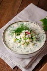 Cold Okroshka Soup with Eggs, Vegetables, Meat, Herbs and Kefir on a Wooden Background, Summer Soup