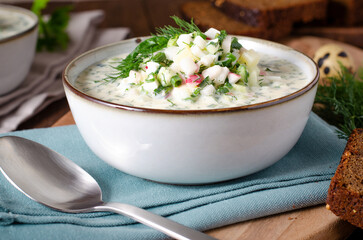 Cold Okroshka Soup with Eggs, Vegetables, Meat, Herbs and Kefir on a Wooden Background, Summer Soup