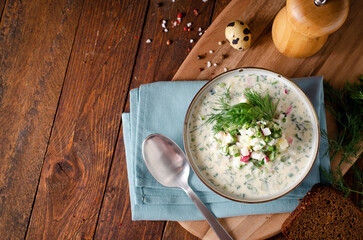 Cold Okroshka Soup with Eggs, Vegetables, Meat, Herbs and Kefir on a Wooden Background, Summer Soup
