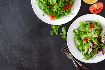 Top view two plates of fresh diet salad on dark background with copy space, delicious healthy food