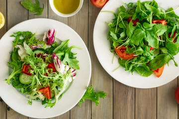 Two plates of fresh diet salad on wooden table, delicious healthy food top view