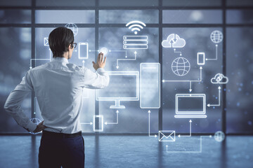 Internet of things, IOT and cloud computing service concept with man back view touching digital screen with devices connected to digital storage in a data center over the Internet on window background
