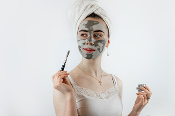 woman in towel with brush applied a black cleansing mask on face isoalted on white