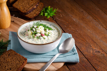 Cold Okroshka Soup with Eggs, Vegetables, Meat, Herbs and Kefir on a Wooden Background, Summer Soup