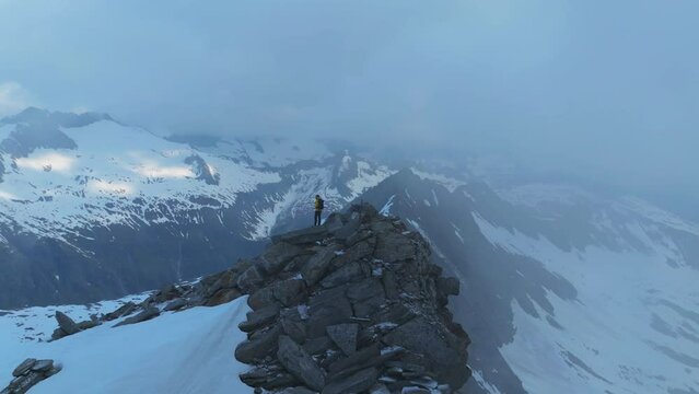 Aerial Footage: Male Mountaineer Standing on Rocky Summit at Sunrise in the Alps (Italy-Austria Border)