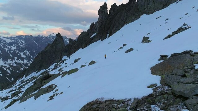 Solo Male Mountaineer Hiking on Snowfield at Sunrise - Aerial Drone Footage