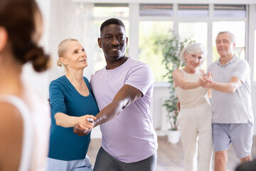 Fototapeta premium Dynamic mature attendees of dancing courses training poses of Waltz in dance hall