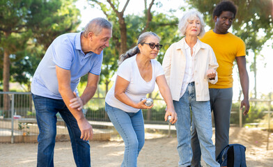 Portrait of mixed-race age-diverse mature men and women standing side by side with metal boules 