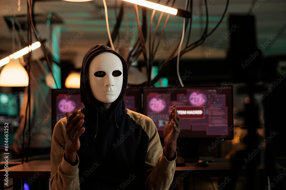 Aufkleber african american hacker broadcasting threat video at night, wearing anonymous mask and asking ransom