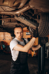 Obraz na płótnie Canvas Portrait of a mechanic repairing a lifted car