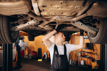 Portrait of a mechanic repairing a lifted car
