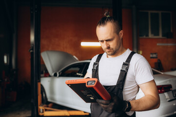 Portrait of young male mechanic with digital tablet at garage.