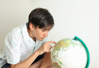 Portrait of a school boy with the globe.  Closeup Young element school kid looking the map learning...