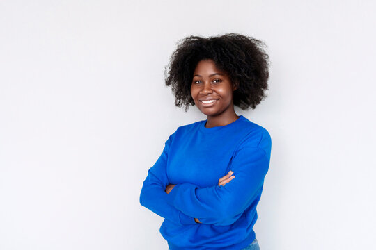 Young Afro woman with arms crossed standing against white background