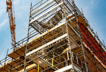 Close up of scaffolding around semi-built flats and apartments on a construction site. Captured on a sunny summer day