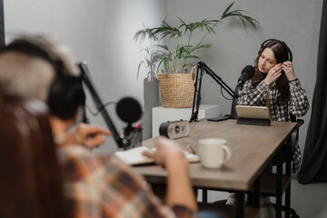 Two bloggers are recording a joint podcast in the studio. Radio station workers are on the air together.