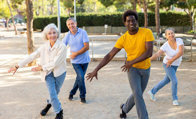 Carefree diverse people spending time together dancing rhythmic dance aerobic workout on a sandy...