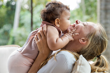 Cheerful mother with baby daughter embracing each other at home