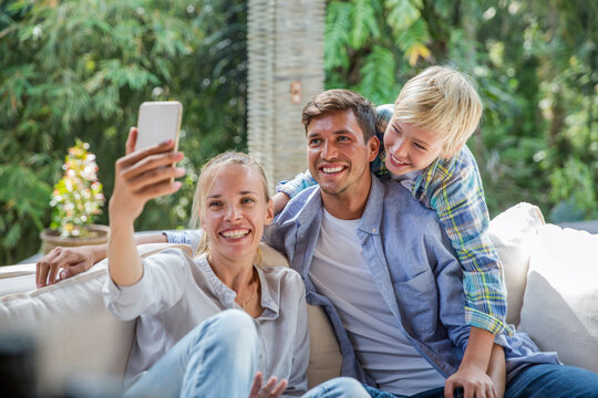 Happy woman taking selfie with family at home