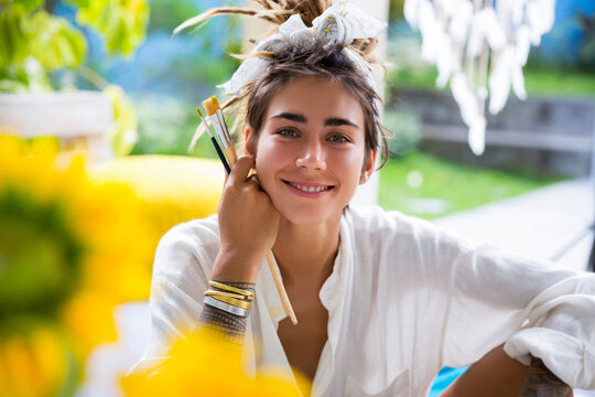 Smiling artist with paintbrush at home
