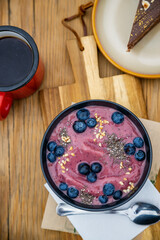 Smoothie bowl with fresh blueberries and chia seeds and black coffee on a wooden table