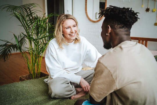 Smiling couple sitting face to face and discussing on bed