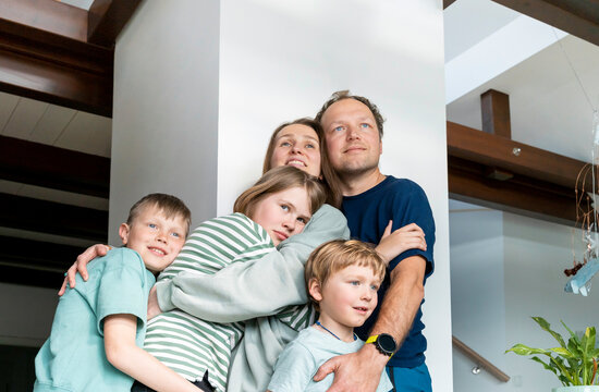 Happy family embracing together by column at home