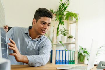 Businessman explaining solar panel on video call through laptop at office