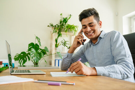 Smiling businessman talking on smart phone in office