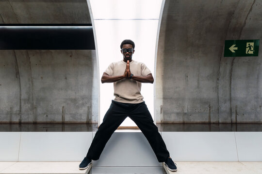 Man with cyber glasses standing wide-legged over gap with prayer hands