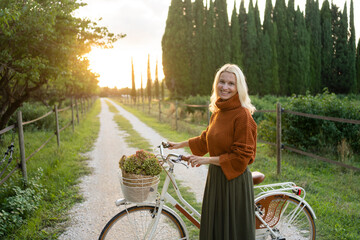 Smiling woman standing next to bicycle on footpath