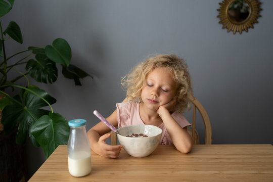 Girl with bowl of cereals sleeping at table