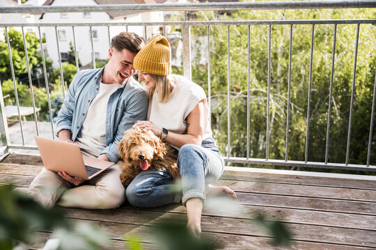 Loving young couple using laptop on balcony