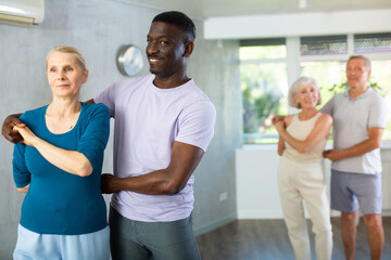 Obraz premium Middle-aged African man is engaged in dance hall with mature female partner and dances Latin rumba. Hobby, healthy lifestyle concept