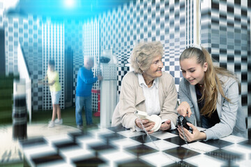 Senior woman and her granddaughter thinking about chess riddle solution in escape room. Old man and...
