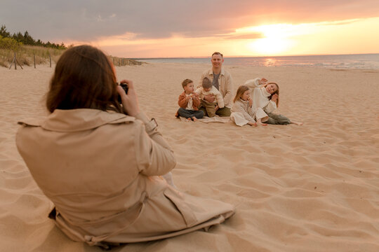 Woman photographing family through camera at beach
