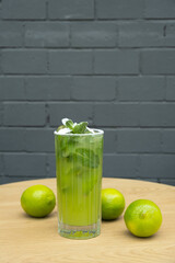 Mojito and limes on a cafe table against a gray brick wall background