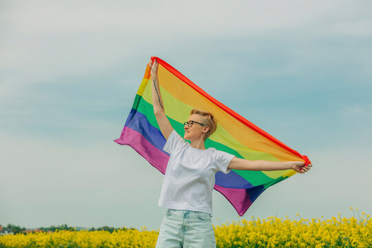 Smiling lesbian holding rainbow flag at field
