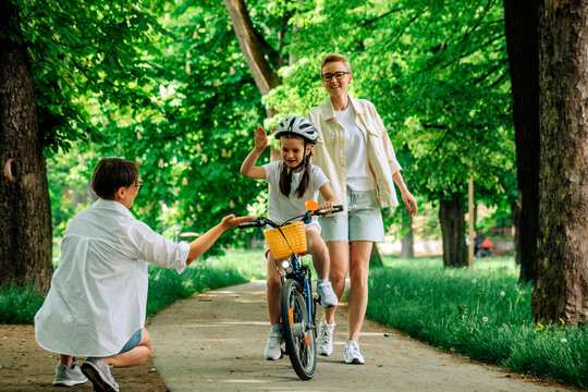 Lesbian mother giving high-five to daughter cycling in park