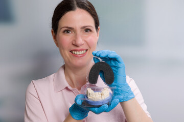 Smiling dentist / Dental technician is presenting a dental imprint with artificial dentition ready for use