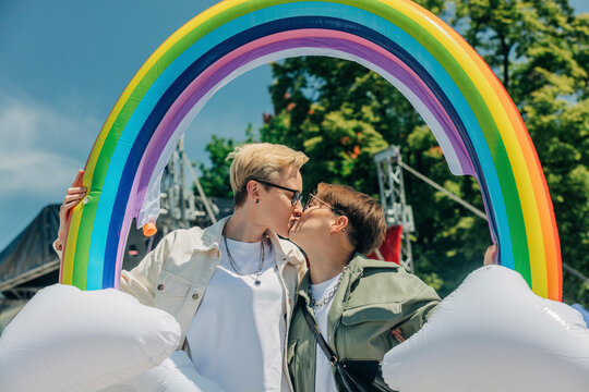 Lesbians with inflatable rainbow kissing each other