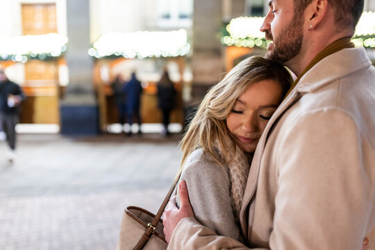 Young woman hugging man at Christmas market - Powered by Adobe