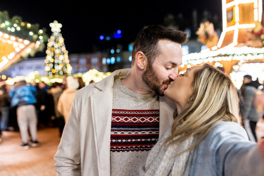 Young woman and man kissing each other at Christmas market