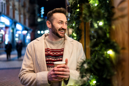 Happy man standing with coffee cup at Christmas market