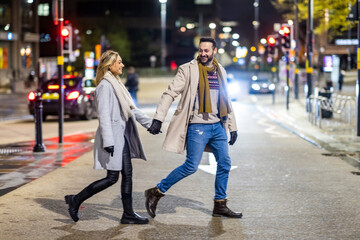 Happy man holding hands with woman and crossing road together