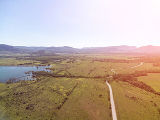 Aerial view on mountain lake. Drone over water reservoir at mountain valley covered with green spring forest. Beautiful view from above on smooth blue surface of mountain lake among highlands. Nobody