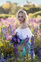 beautiful blond woman in white dress on lupin field summer background close up portrait