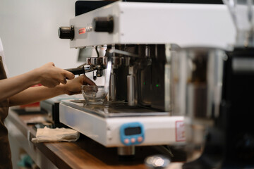 Young barista making coffee, coffee preparation service concept.